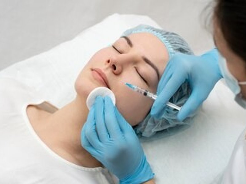 A practitioner preparing a patient's cheek for a needle-based treatment